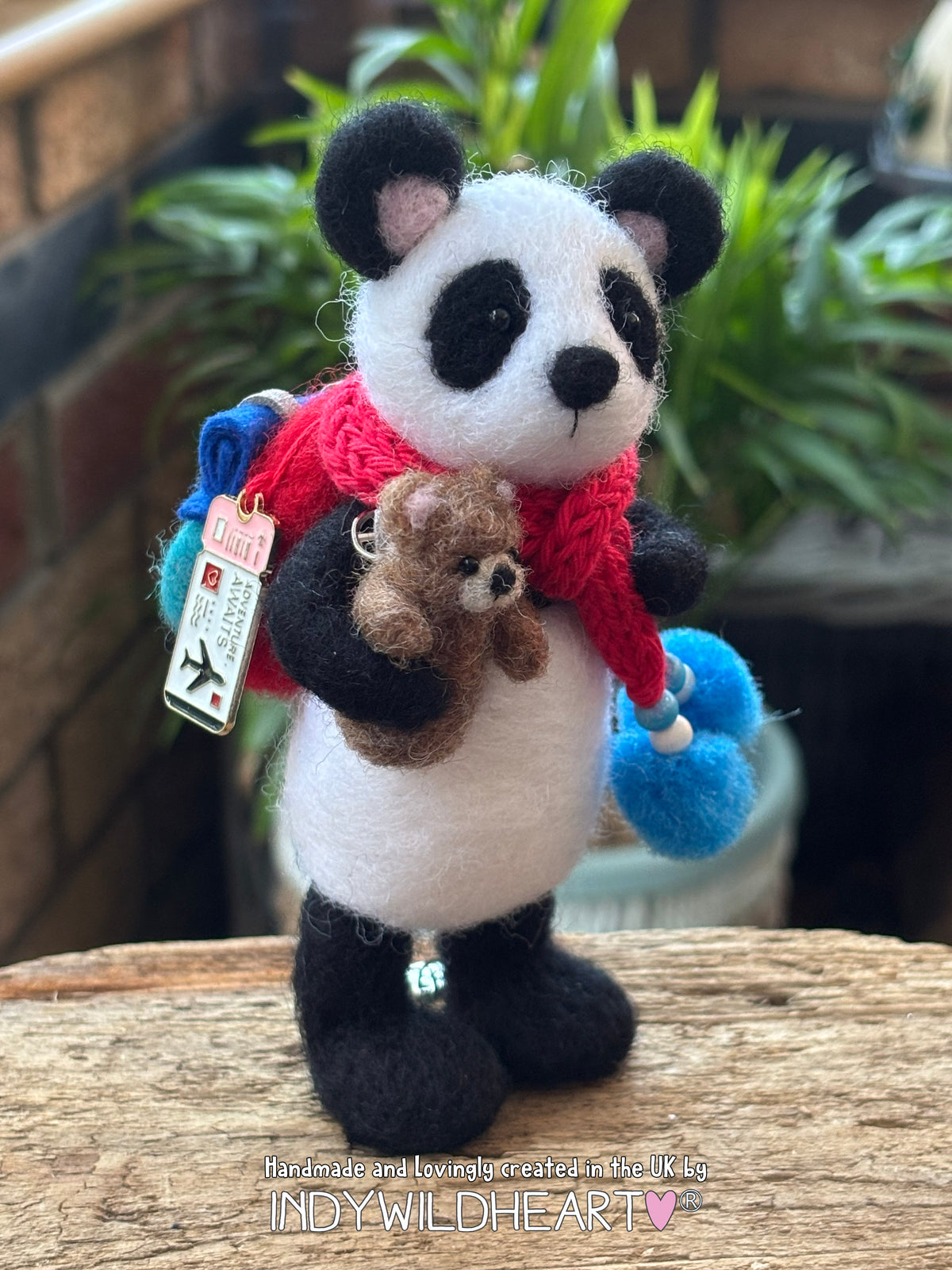 Needle Felted Panda Collectible character wearing a blue and red rucksack and scarf and holding a miniature needle felted teddy