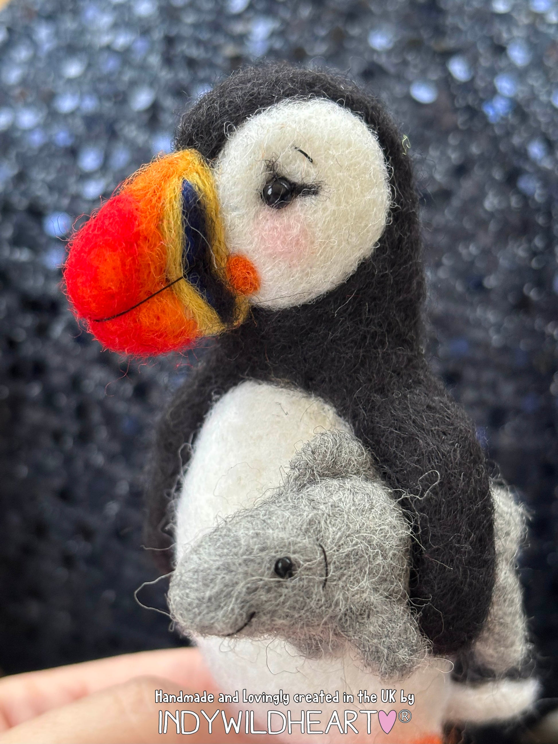 Felted puffin with a fish on a textured black background