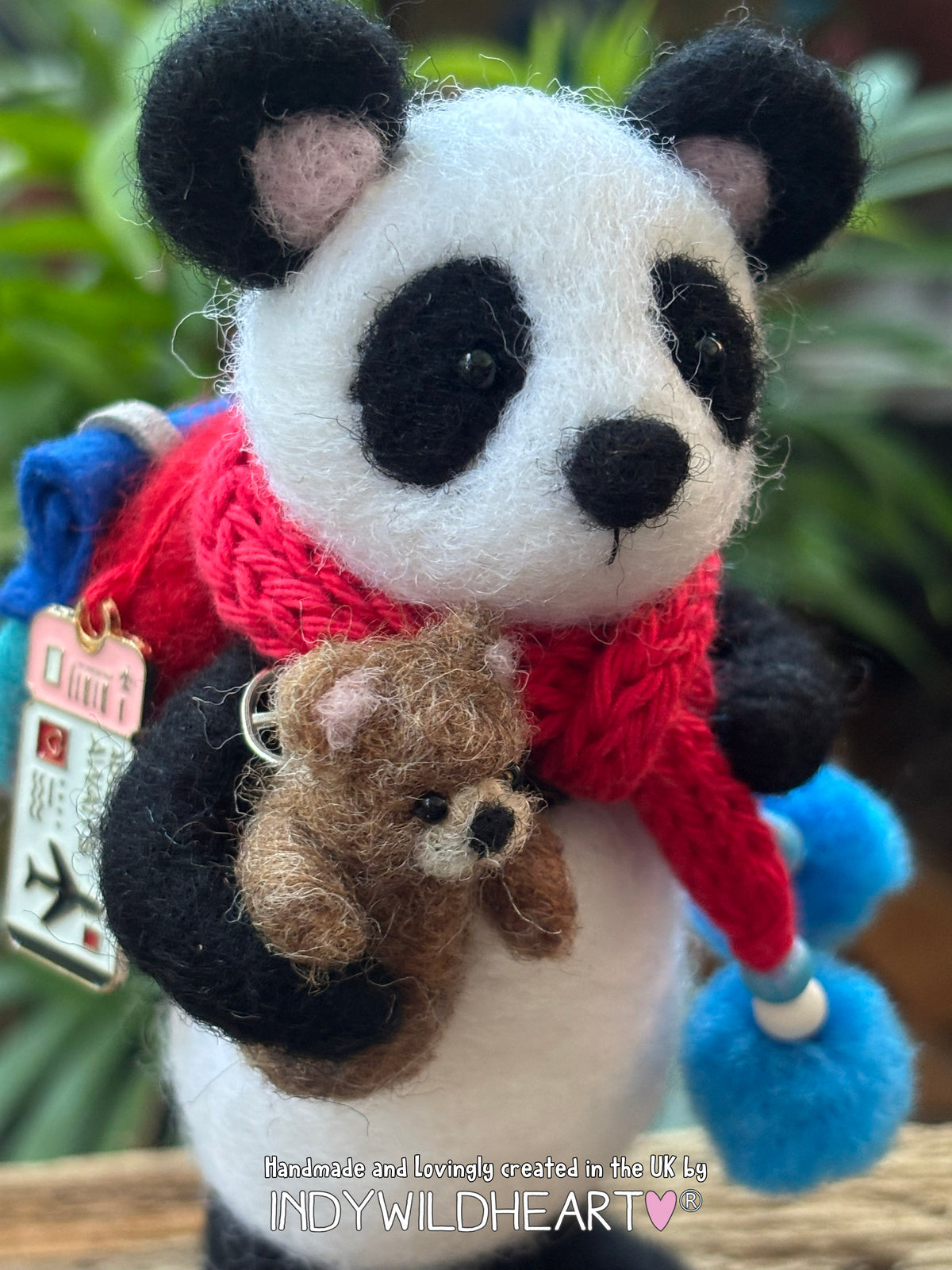 Needle Felted Panda Collectible character wearing a blue and red rucksack and scarf and holding a miniature needle felted teddy