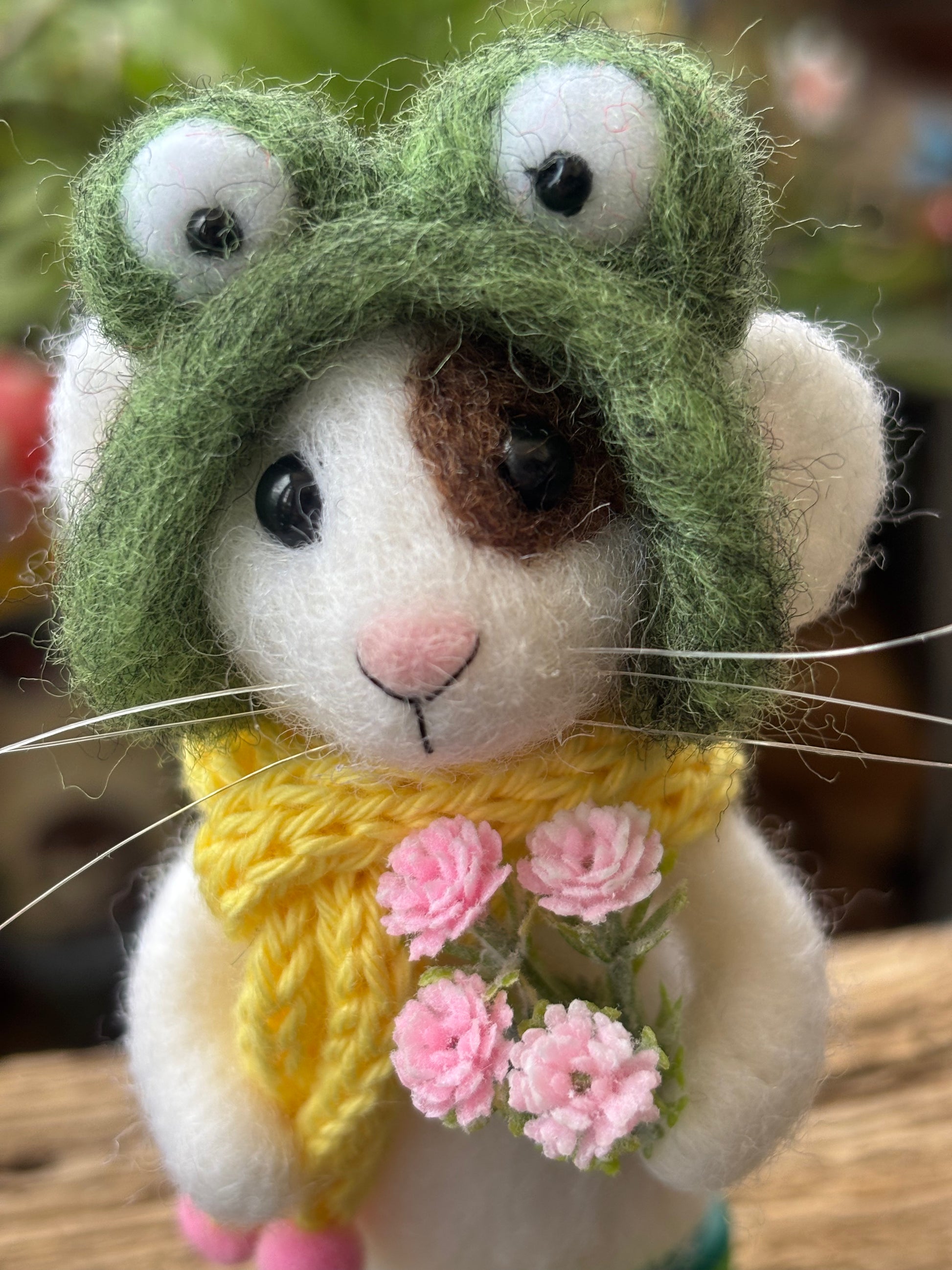 felted mouse in a green frog hat and yellow scarf with pink flowers